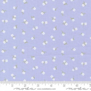 May include: A light purple fabric with a repeating pattern of small white flowers and green stems. The fabric has a ruler printed along the bottom edge, with the word "moda" and website address printed below.
