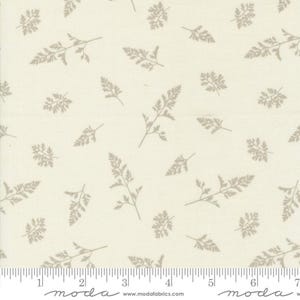 May include: A white fabric with a repeating pattern of small, gray sprigs of leaves. The fabric is marked with a ruler in inches.