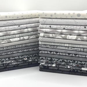 May include: Two stacks of folded fabric squares featuring a variety of monochromatic patterns in shades of gray, black, and white. The designs include polka dots, botanical prints, spider webs, skulls, geometric shapes, and measuring tape motifs.