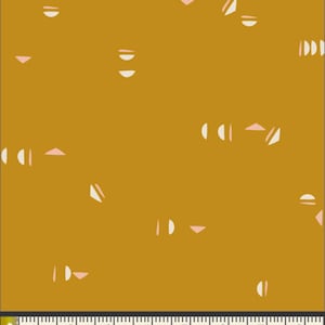 May include: Mustard-colored fabric with a repeating pattern of white half-circles, pink triangles, and white angled lines. The fabric is measured with a ruler showing inches.