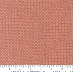 May include: A close-up of a fabric with a repeating pattern of small, light orange circles on a darker orange background. The fabric has a textured appearance. A ruler is at the bottom of the image, with the word "moda" printed on it.