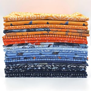 May include: A vertical stack of folded fabric pieces featuring a gradient colour palette transitioning from warm orange and gold tones at the top to cool blue and dark navy shades at the bottom, with various printed patterns including florals and lines.