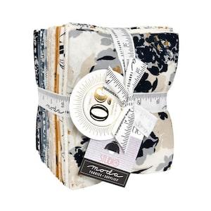 May include: A stack of fabric squares tied with a measuring tape ribbon. The fabric features a floral pattern in shades of white, gray, navy, and gold. The ribbon and tags display the "Moda Fabrics" logo and text.
