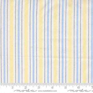 May include: Fabric with vertical stripes in light blue, yellow, and white. The stripes are evenly spaced and run the length of the fabric. The fabric has a textured appearance and is likely cotton or a similar material. The bottom edge has a ruler printed on it.