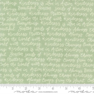 May include: A light green fabric with white cursive text repeating phrases like "Kindness is Love in Action" and "Scatter seeds of Kindness." A ruler is at the bottom. The fabric is from Moda Fabrics.