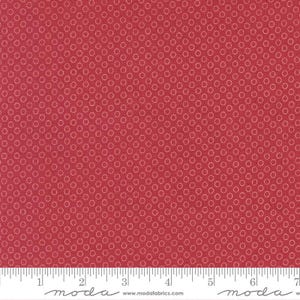 May include: Red fabric with a repeating pattern of small, light-colored circles. The fabric has a ruler along the bottom edge, marked in inches. The fabric is likely used for quilting or other sewing projects.
