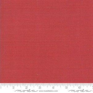 May include: A solid red fabric swatch with a subtle woven texture. The fabric is measured in inches with a ruler that reads "moda" at the 2-inch and 6-inch marks.
