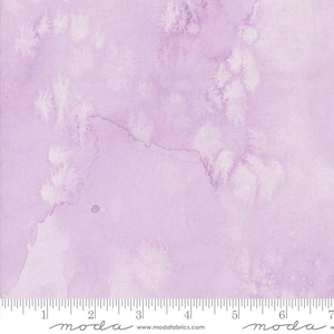May include: A light purple watercolour fabric with a subtle white pattern. The fabric has a soft, dreamy feel and is perfect for quilting, crafts, and home decor.