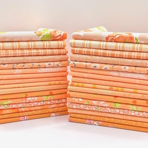 May include: Two stacks of folded fabric in various shades of orange. The fabric patterns include stripes, floral, and geometric designs. The stacks are neatly arranged, showcasing a variety of textures and prints, perfect for quilting or crafting projects.