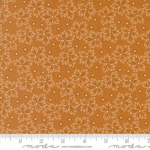 May include: A brown fabric with a white floral pattern. The fabric has a repeating pattern of small white dots and larger white flowers with a dotted outline. The fabric is shown with a ruler in inches.