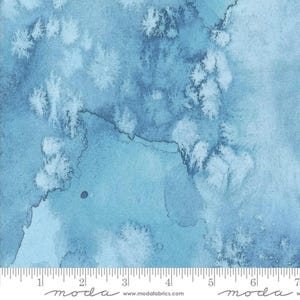 May include: Abstract watercolour fabric in shades of blue with white splatter paint. The fabric is marked with a ruler in inches and the word "moda" is printed on the fabric.
