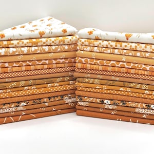 May include: Two stacks of folded fabric squares in various shades of orange, mustard, and cream. The textiles feature diverse patterns including floral prints, geometric shapes, polka dots, stripes, and botanical motifs, all neatly layered.