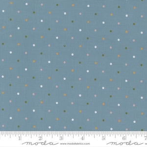 May include: A blue fabric with a repeating pattern of small, evenly spaced polka dots in white, pink, green, and gold. The fabric has a textured appearance and a ruler is at the bottom.