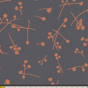 May include: A dark gray fabric with a repeating pattern of small, orange-colored floral sprigs. The fabric is measured with a ruler in inches.