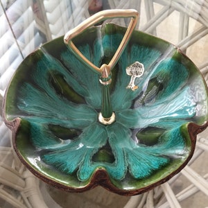 May include: A vintage Sequoia ceramic serving dish with a teal and green floral design. The dish has a gold-toned handle and a Sequoia label. The dish is approximately 10 inches in diameter.