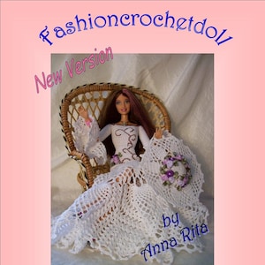 Può includere: Un abito da bambola in crochet bianco con una corona di fiori viola, seduto su una sedia di vimini. L'abito ha un motivo a pizzo e la bambola ha lunghi capelli castani e occhi azzurri. Il testo "Fashioncrochetdoll New Version by Anna Rita Summer" è sull'immagine.
