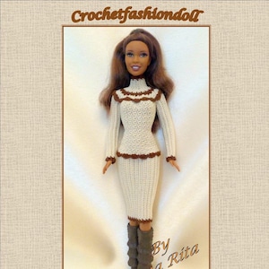 Può includere: Un vestito all'uncinetto per una bambola in colori crema e marrone. Il vestito ha un top a maglione a maniche lunghe e una gonna. La bambola indossa stivali marroni. Il testo "Vestito crema e marrone" è nella parte inferiore dell'immagine. Il testo "Di Anna Rita" è nell'angolo in alto a destra dell'immagine.