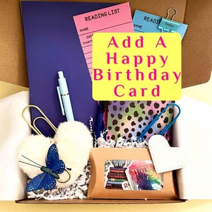 May include: A gift box filled with stationery items, including a purple notebook, pink reading list, and a light blue pen. The box also contains a butterfly decoration, a heart-shaped tag, and a card that says "Add A Happy Birthday Card."