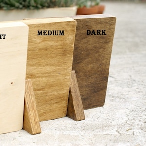 May include: Three wooden blocks, each stained a different shade of brown. The blocks are labeled "LIGHT", "MEDIUM", and "DARK".