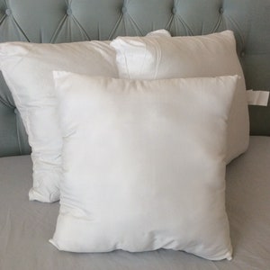 May include: Three white pillows on a light gray bed with a light blue tufted headboard.