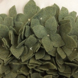 May include: A close-up of a green felt flower arrangement. The flowers are made of individual felt petals sewn together to create a 3D effect.