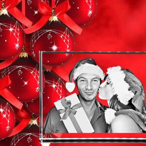 May include: A 3D crystal photo frame with a black and white image of a couple in Santa hats. The man is holding a wrapped gift and the woman is kissing him on the cheek. The frame is sitting on a red background with red Christmas ornaments.