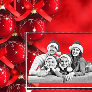 May include: A crystal cube with a black and white photo of a family wearing Santa hats. The photo shows a family of four, including two children, smiling and looking at the camera. The background of the photo is a red and white Christmas theme.