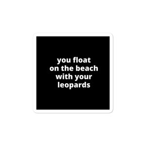May include: Square sticker with a black background and white text that reads "you float on the beach with your leopards". The sticker has a white border.