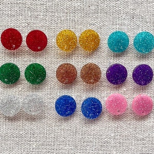 May include: A set of 12 round, glitter-covered earrings in various colors, including red, green, blue, gold, silver, purple, and pink.