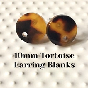 May include: Two 10mm (approx. 0.4 inches) tortoise shell earring blanks. The blanks are round with a hole for attaching to earring posts. The blanks have a brown and yellow pattern. Text reads "10mm Tortoise Earring Blanks".