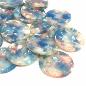 May include: A pile of round, white, blue, and pink marbled plastic discs. The discs have a glossy finish and are about 1 inch in diameter.