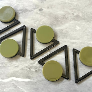 May include: Four black triangle-shaped frames with a green circle inside each frame. The frames are made of plastic and have a glossy finish.