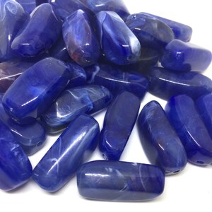 May include: A pile of blue and white marbled glass beads. The beads are oval shaped and have a smooth, glossy finish.