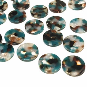 May include: A collection of round, flat beads with a marbled pattern. The beads feature a mix of teal, brown, black, and white colors. The beads are scattered across a white surface.
