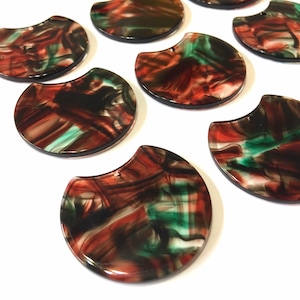 Op de afbeelding: Een set van tien halfronde hars cabochons met een marmerpatroon in tinten rood, groen en zwart.
