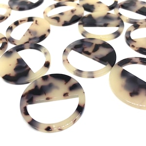 May include: A group of round, white and brown patterned, plastic, decorative rings with a cut-out section in the middle.