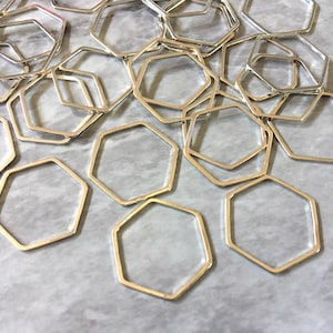 May include: A pile of silver-toned metal hexagonal rings. The rings are all the same size and shape, and they are arranged in a random pattern.