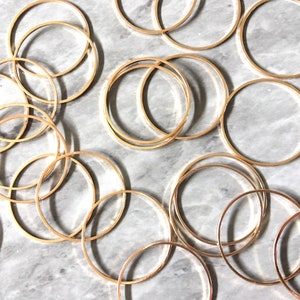 May include: A collection of gold-toned metal hoops of varying sizes, arranged on a white marble surface.