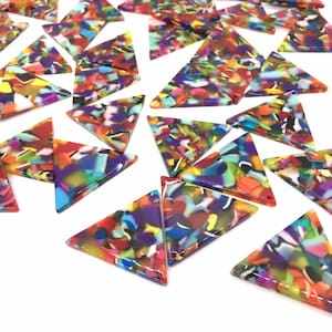 May include: A collection of colourful, triangular, resin craft supplies. The triangles are made of clear resin with a variety of colours and patterns embedded inside. The resin is translucent, allowing the colours to shine through.
