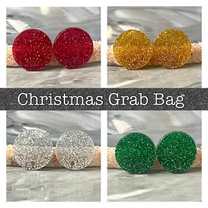 May include: A collection of four pairs of round, glittery earrings in red, gold, silver, and green. The text "Christmas Grab Bag" is displayed in a silver font on a black background.