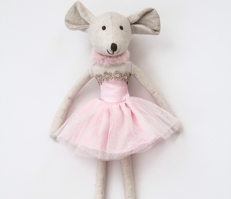 May include: A gray and white fabric mouse doll wearing a pink tulle tutu with gold trim and a white fur collar.