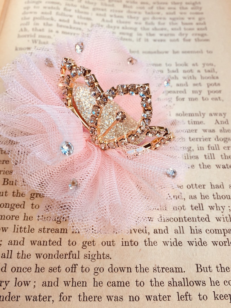 Pode incluir: Uma delicada flor de tule rosa com um prendedor de cabelo de borboleta dourado adornado com strass brilhantes. A borboleta tem um acabamento brilhante e &eacute; um belo acento para qualquer penteado.