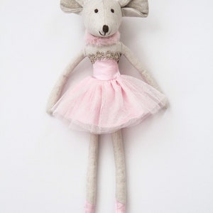 May include: A gray and white fabric mouse doll wearing a pink tulle tutu with a gold trim. The doll has long legs and is standing on a white background.