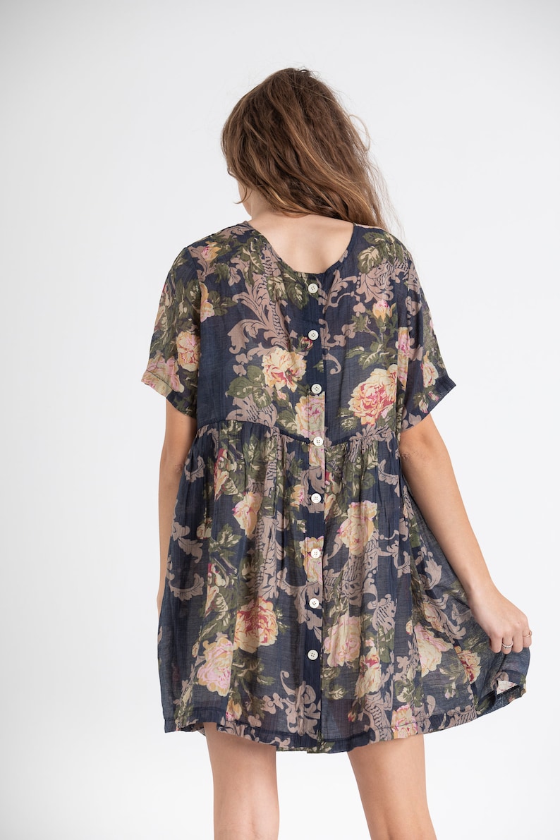 Puede incluir: Un vestido corto de flores azul marino con botones en la espalda. El vestido tiene un corte holgado y mangas cortas.