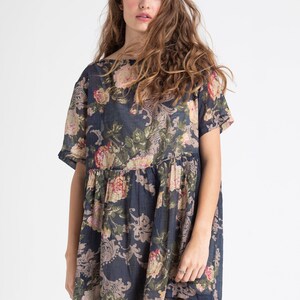 Puede incluir: Un vestido azul marino de manga corta con estampado floral. El vestido tiene un corte holgado y una cintura fruncida.