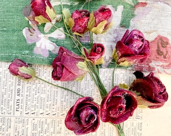 May include: A bouquet of burgundy velvet roses with green stems and leaves. The roses are arranged in a cluster and are in various stages of bloom.