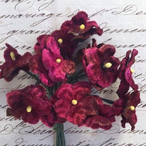 May include: A bunch of burgundy velvet flowers with yellow centers. The flowers are arranged in a bouquet and are ready to be used for crafting or decorating.