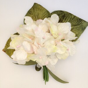 May include: A bouquet of white and light pink felt flowers with green felt leaves. The flowers have a delicate, vintage look.
