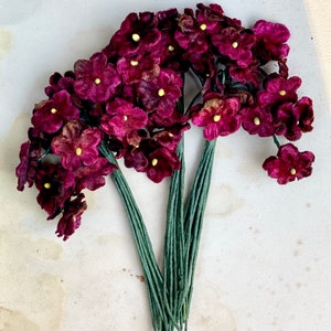 May include: A bunch of deep purple velvet flowers with yellow centers on green stems. The flowers are arranged in a bouquet.