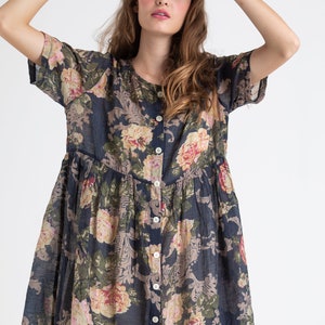 Puede incluir: Un vestido de estampado floral azul marino con mangas cortas y botones en la parte delantera. El vestido tiene una falda fruncida y un corte holgado.